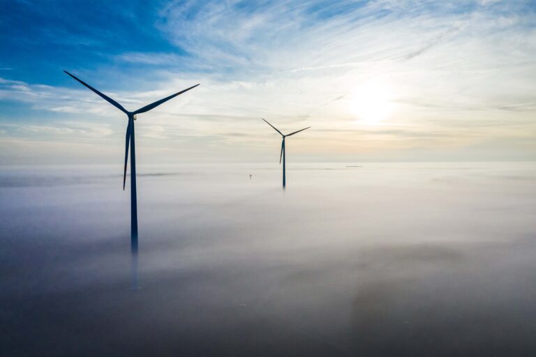 Wind turbines in morning fog at sunrise, renewable energy production in Estonia.